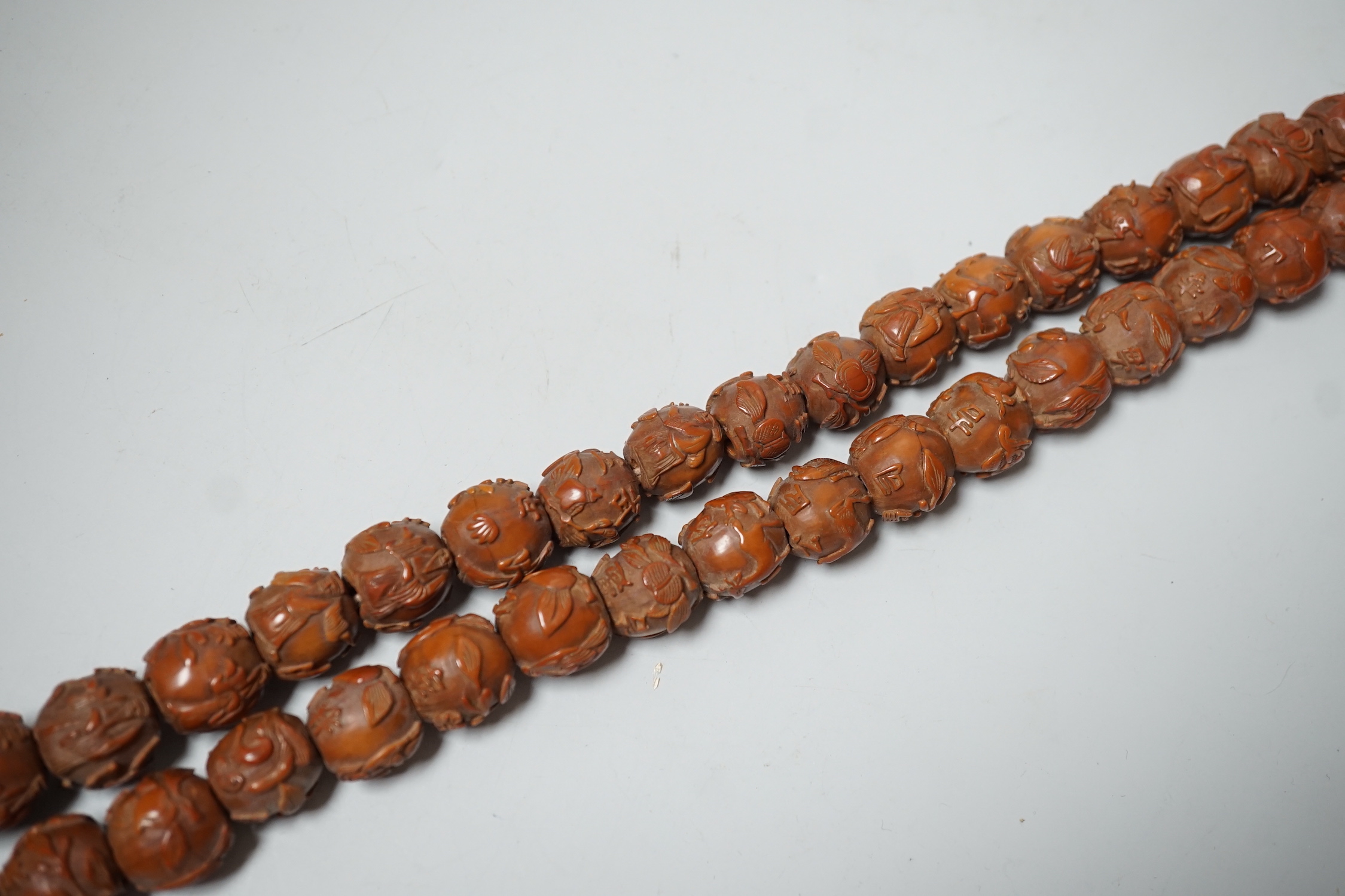 A Chinese necklace of 94 carved coquilla nuts/peach stones